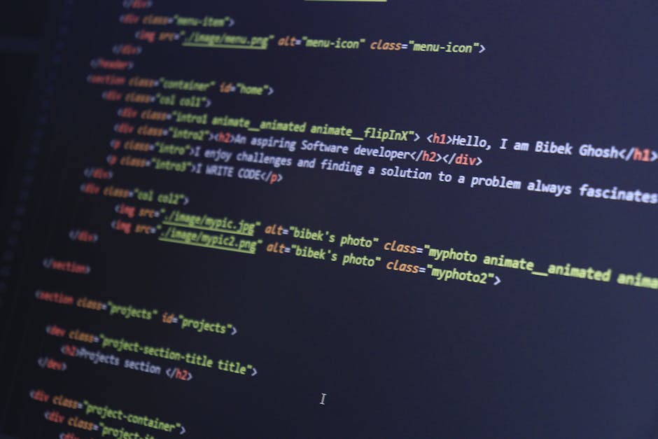 The image displays a close-up of a MacBook Pro laptop on a white desk, with the screen showing a code editor window filled with JavaScript, HTML, and CSS scripts related to a web application. The code